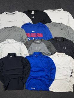 flatlay of mixed Nike and Under Armour compression t shirts for gym and sport